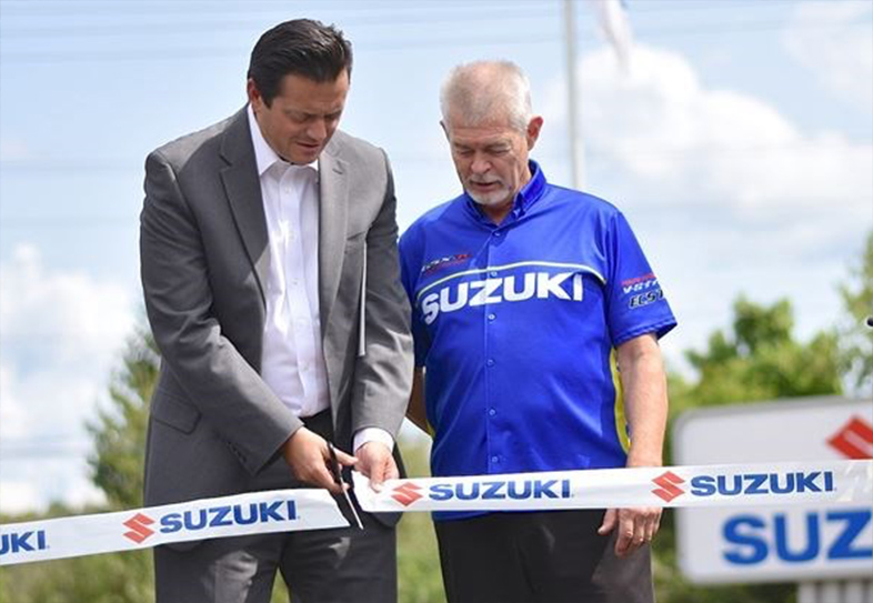 Two men cutting Suzuki ribbon at event